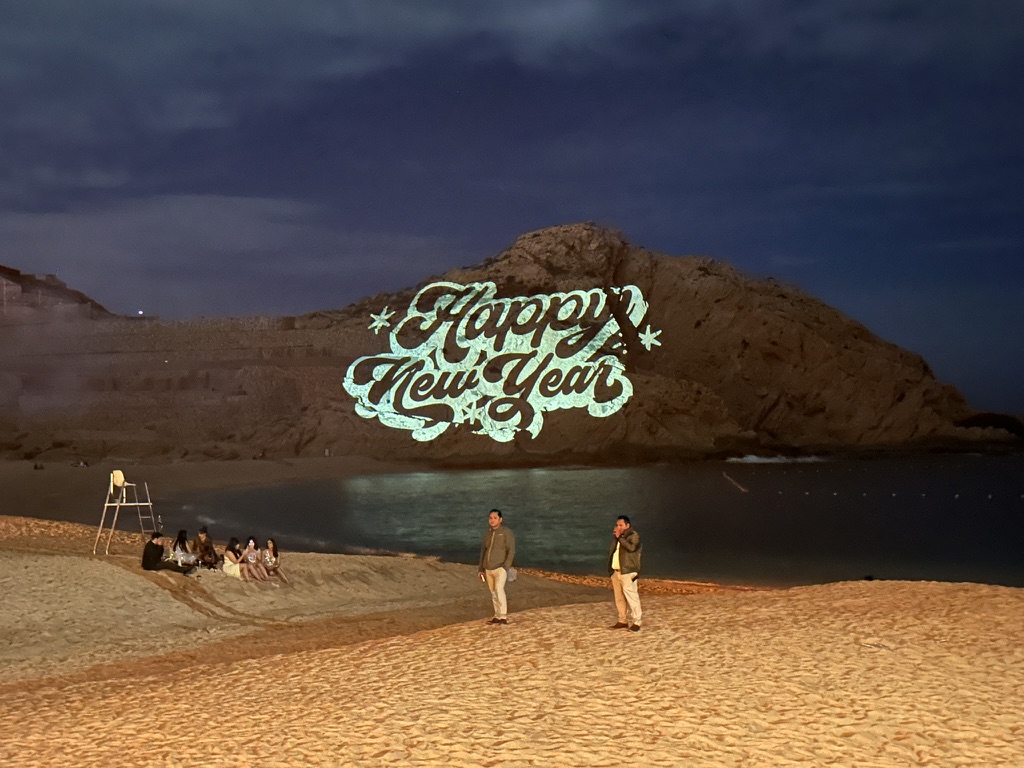 Happy New Year gobo projected onto cliff face over beach Cabo San Lucas NYE production