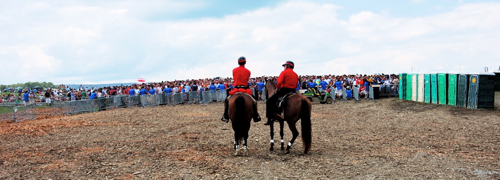Mounted security on horseback overlooking crowd and perimeter barricades at festival
