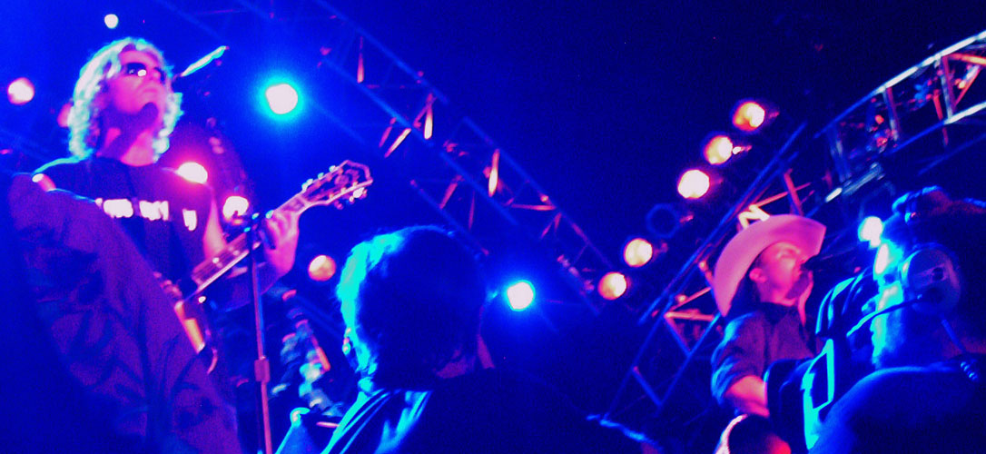 Musicians performing under blue and purple stage lighting sidestage view