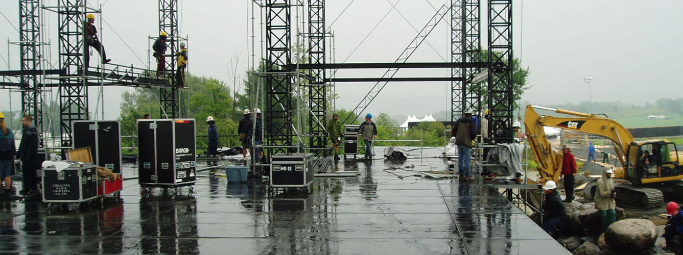 Stage build in rain crew working wet deck with equipment cases Phish IT Festival 2003